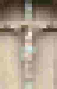 Detailreiche Jesusfigur am Kruzifix mit goldenen Dornenkrone vor holzverkleideter Wand.